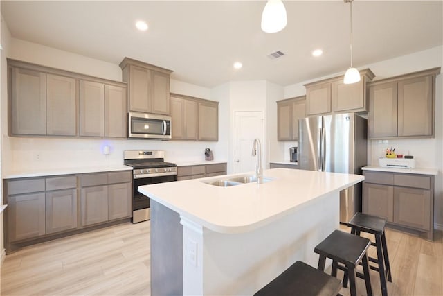 kitchen with pendant lighting, sink, appliances with stainless steel finishes, and light hardwood / wood-style flooring