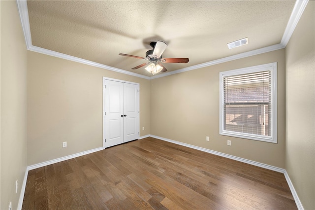 unfurnished bedroom with ornamental molding, ceiling fan, a closet, and hardwood / wood-style floors