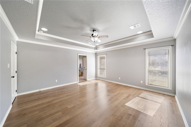 unfurnished room featuring a textured ceiling, hardwood / wood-style floors, a tray ceiling, crown molding, and ceiling fan