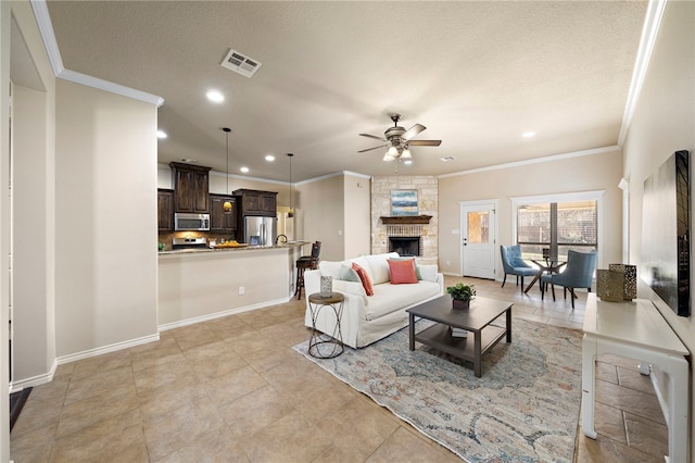 tiled living room with ceiling fan, a stone fireplace, and ornamental molding