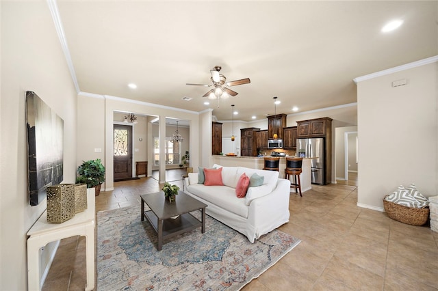 living room featuring ceiling fan with notable chandelier and ornamental molding