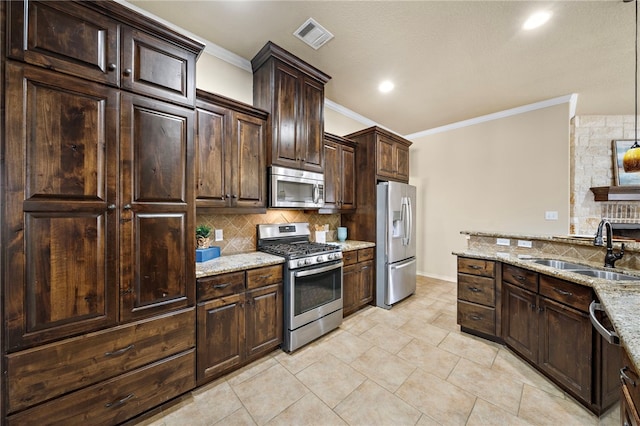 kitchen featuring light stone counters, pendant lighting, sink, stainless steel appliances, and dark brown cabinetry