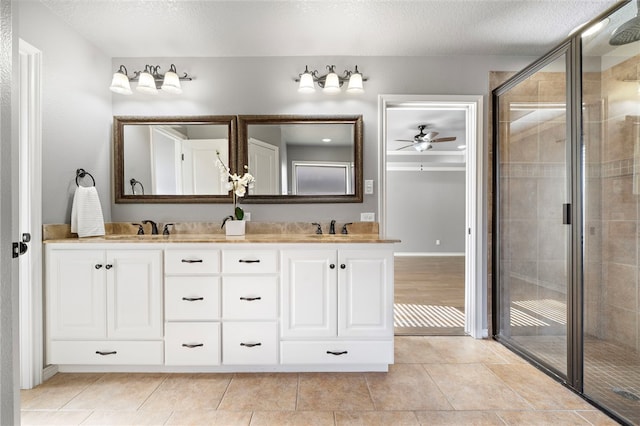 bathroom featuring ceiling fan, a textured ceiling, vanity, and a shower with shower door