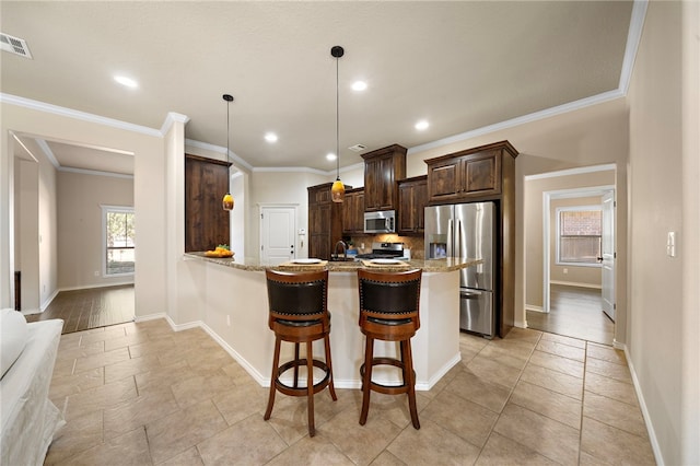 kitchen featuring decorative light fixtures, a kitchen breakfast bar, kitchen peninsula, light stone countertops, and appliances with stainless steel finishes