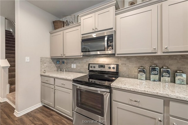 547 Hayes Ln, College Station, TX 77845 - kitchen featuring appliances with stainless steel finishes, dark wood-type flooring, tasteful backsplash, and light stone countertops
