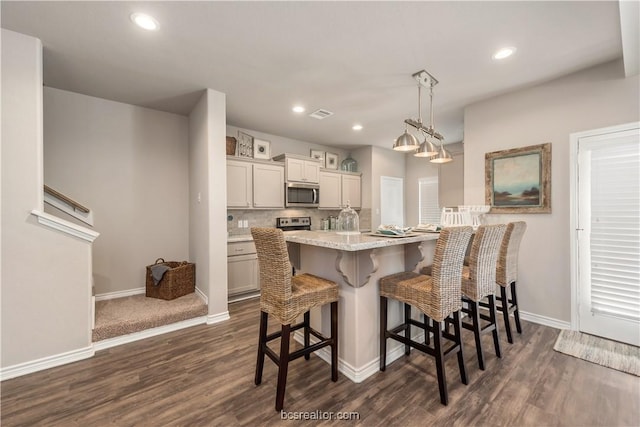 547 Hayes Ln, College Station, TX 77845 - kitchen featuring stainless steel microwave, a kitchen breakfast bar, dark wood finished floors, and recessed lighting