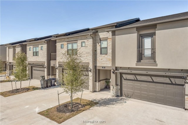 547 Hayes Ln, College Station, TX 77845 - view of front facade featuring stone siding, an attached garage, driveway, and solar panels