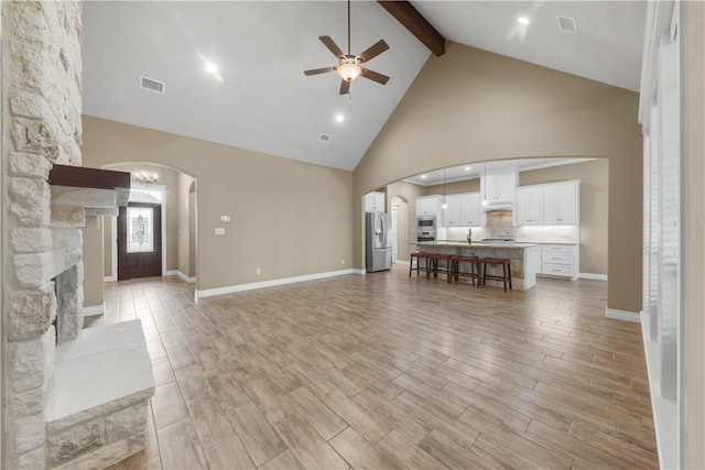 3520 Foxcroft Path, Bryan, TX 77808 - living room featuring ceiling fan, high vaulted ceiling, beamed ceiling, arched walkways, and light wood-style flooring
