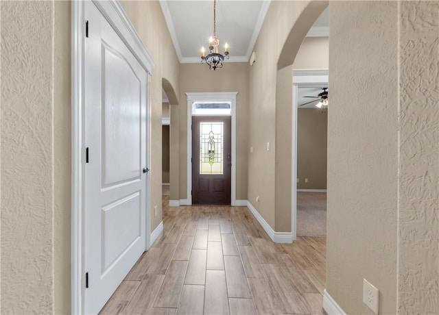 3520 Foxcroft Path, Bryan, TX 77808 - foyer entrance featuring arched walkways, ornamental molding, a textured wall, ceiling fan, and a chandelier