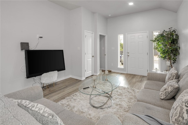 living room with light wood-type flooring and vaulted ceiling