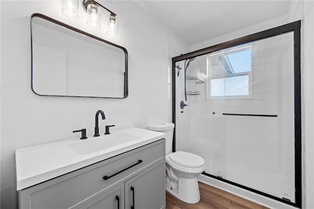 bathroom featuring walk in shower, hardwood / wood-style floors, vanity, and toilet