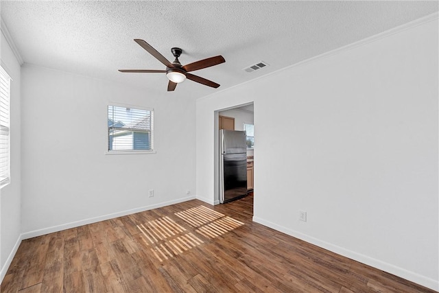 empty room with a textured ceiling, ceiling fan, dark hardwood / wood-style floors, and ornamental molding