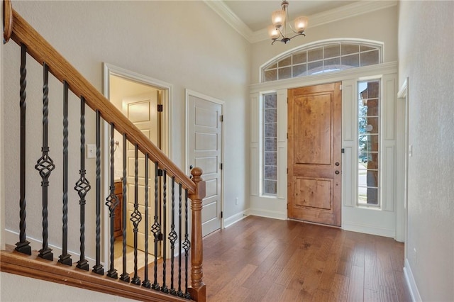 entrance foyer with a wealth of natural light, crown molding, dark hardwood / wood-style flooring, and a notable chandelier