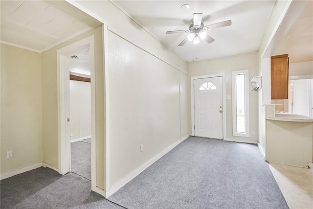 carpeted entryway with ceiling fan and ornamental molding