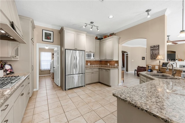 kitchen with built in appliances, arched walkways, light stone countertops, and crown molding