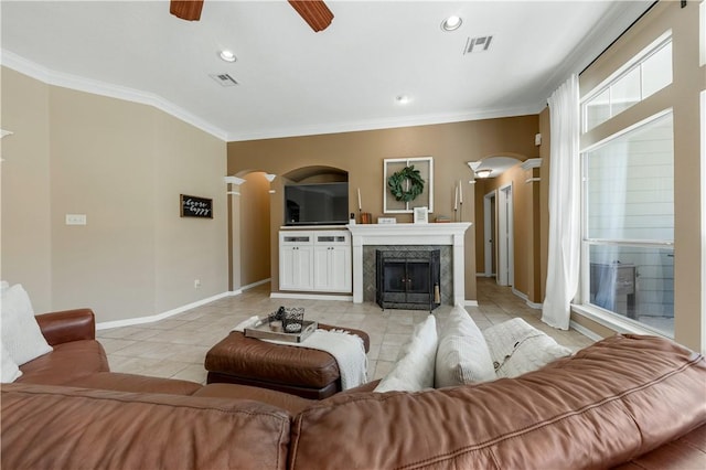 living room featuring arched walkways, crown molding, visible vents, and a ceiling fan