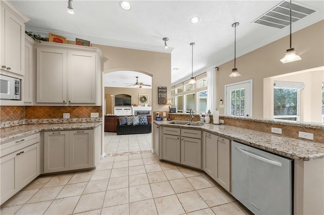 kitchen featuring visible vents, arched walkways, dishwasher, white microwave, and a sink