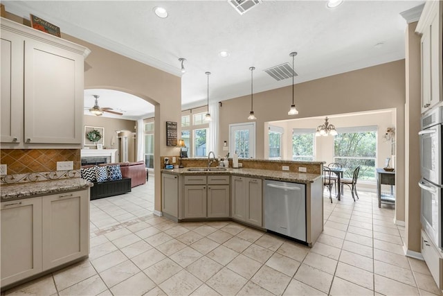 kitchen featuring stainless steel appliances, a fireplace, a sink, visible vents, and decorative backsplash