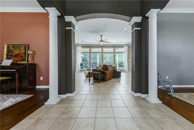 corridor featuring light wood-type flooring, ornate columns, baseboards, and crown molding