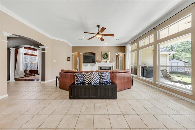 living area with a wealth of natural light, arched walkways, ornate columns, and light tile patterned floors