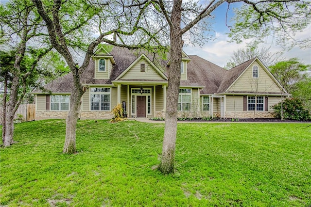 view of front facade with stone siding, fence, and a front yard