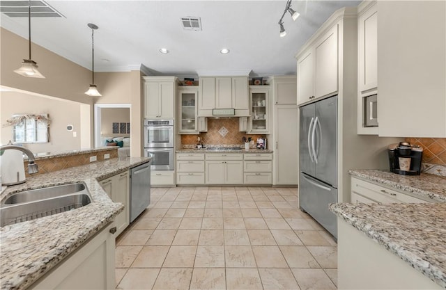 kitchen with a sink, visible vents, appliances with stainless steel finishes, tasteful backsplash, and decorative light fixtures