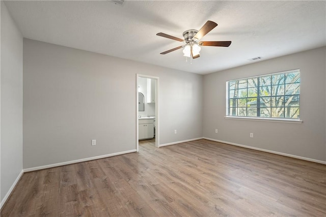 unfurnished bedroom featuring ceiling fan, connected bathroom, a textured ceiling, and light wood-type flooring