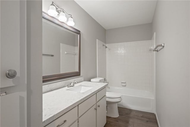 full bathroom featuring hardwood / wood-style flooring, tiled shower / bath, vanity, and toilet