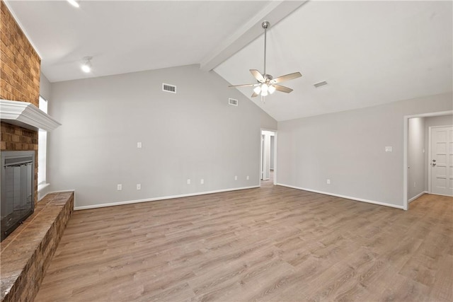 unfurnished living room featuring light hardwood / wood-style flooring, ceiling fan, a fireplace, and beamed ceiling