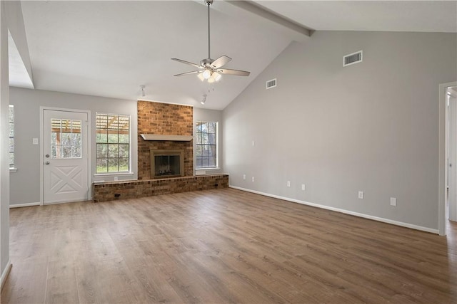 unfurnished living room with hardwood / wood-style flooring, ceiling fan, high vaulted ceiling, a brick fireplace, and beamed ceiling