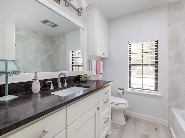 bathroom featuring hardwood / wood-style flooring, plenty of natural light, toilet, and vanity