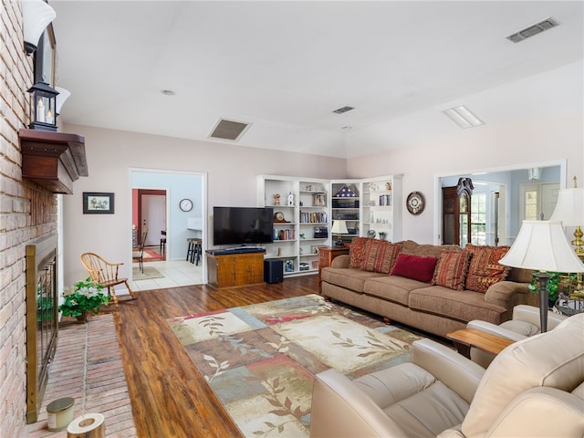 living room with light wood-type flooring and a brick fireplace