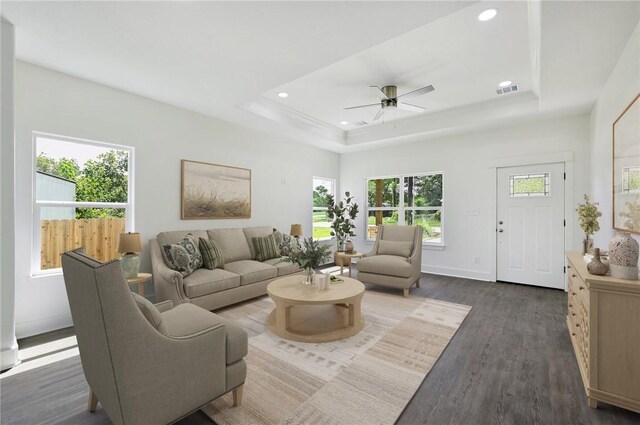 unfurnished living room featuring a tray ceiling, ceiling fan, and dark wood-type flooring