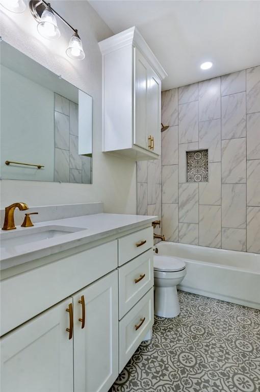 full bathroom with vanity, tiled shower / bath combo, and toilet