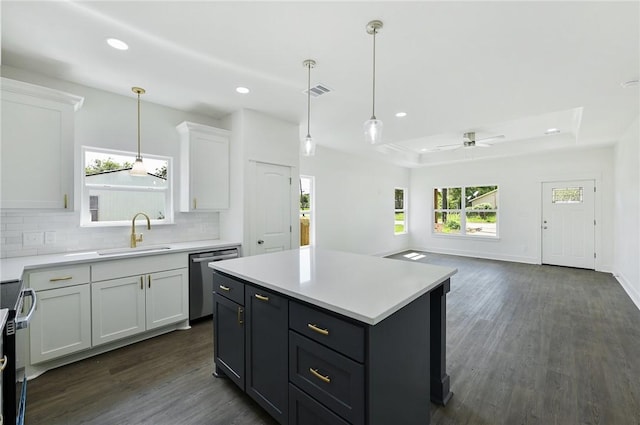 kitchen featuring stainless steel appliances, a raised ceiling, ceiling fan, white cabinets, and a kitchen island