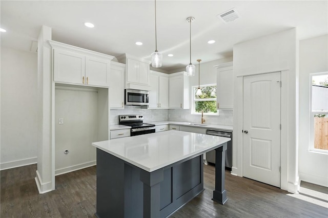 kitchen featuring pendant lighting, a center island, white cabinets, dark hardwood / wood-style flooring, and stainless steel appliances