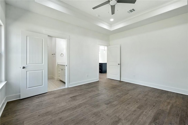 unfurnished bedroom featuring hardwood / wood-style floors, a raised ceiling, ceiling fan, ornamental molding, and connected bathroom