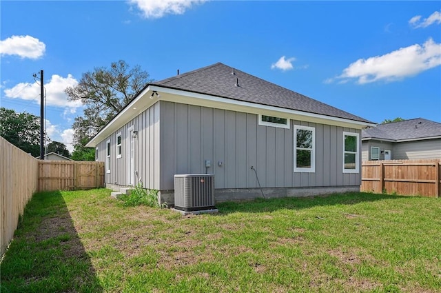 rear view of house featuring central AC and a lawn