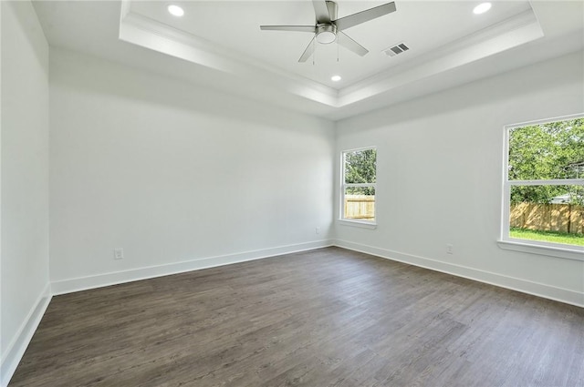 empty room with ceiling fan, a raised ceiling, ornamental molding, and dark wood-type flooring