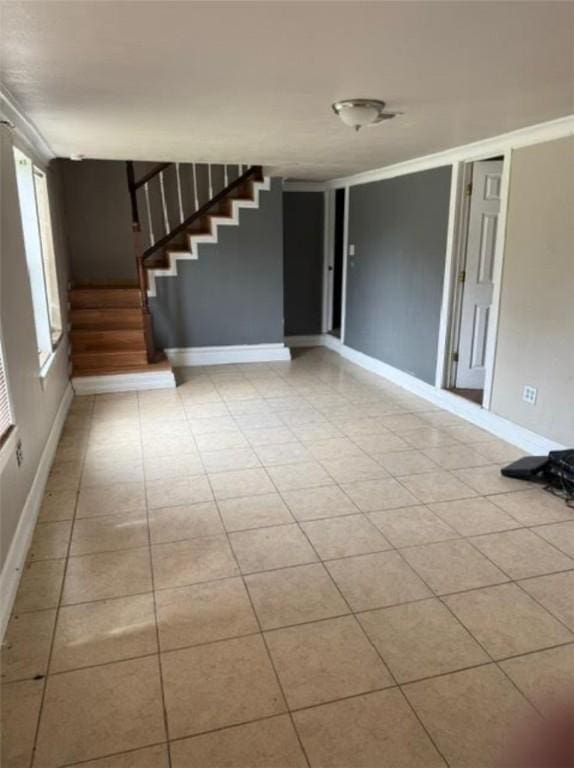 unfurnished living room featuring stairs, baseboards, and tile patterned flooring