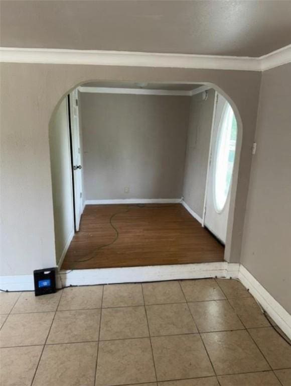 tiled foyer with crown molding, arched walkways, and baseboards