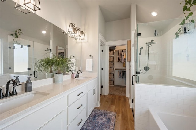 bathroom with hardwood / wood-style flooring, plus walk in shower, and vanity