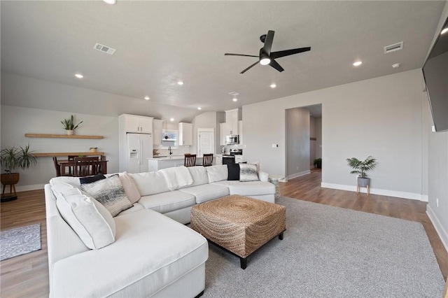 living room with light hardwood / wood-style floors, ceiling fan, and sink