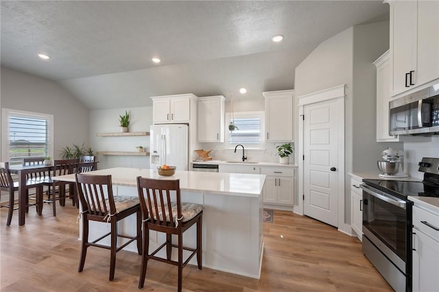 kitchen featuring white cabinetry, vaulted ceiling, a kitchen island, and stainless steel appliances