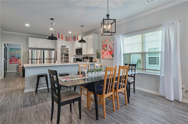 303 Luther St, College Station, TX 77840 - dining room with baseboards, a chandelier, crown molding, wood finished floors, and recessed lighting