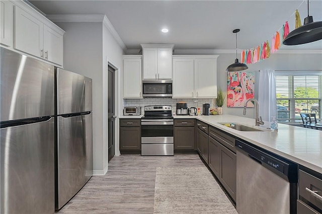 303 Luther St, College Station, TX 77840 - kitchen with appliances with stainless steel finishes, a sink, crown molding, light countertops, and light wood finished floors
