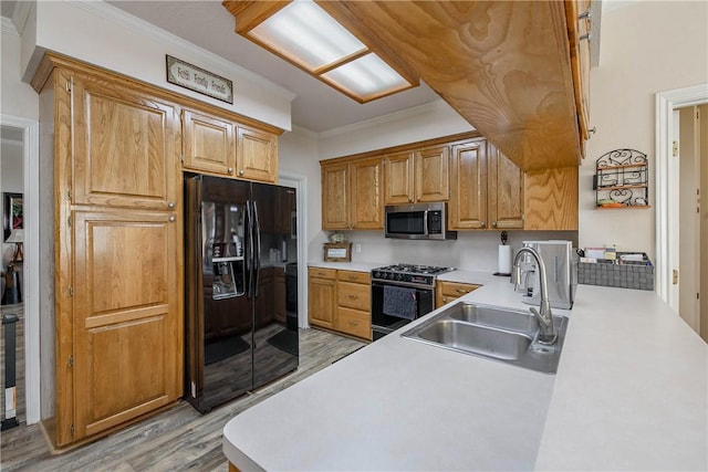 kitchen with sink, light hardwood / wood-style flooring, kitchen peninsula, crown molding, and black appliances