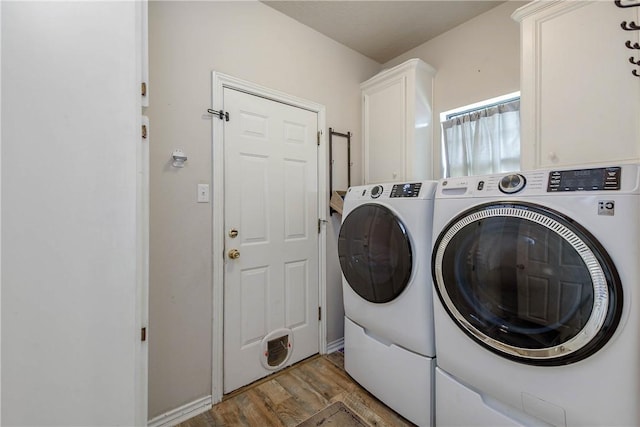 washroom featuring cabinets, light hardwood / wood-style flooring, and washer and clothes dryer