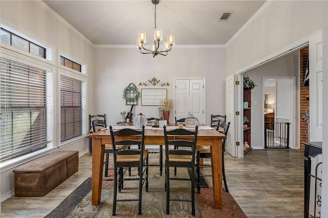 dining area featuring dark hardwood / wood-style floors, ornamental molding, and a chandelier