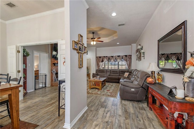 living room featuring wood-type flooring, ceiling fan, and crown molding